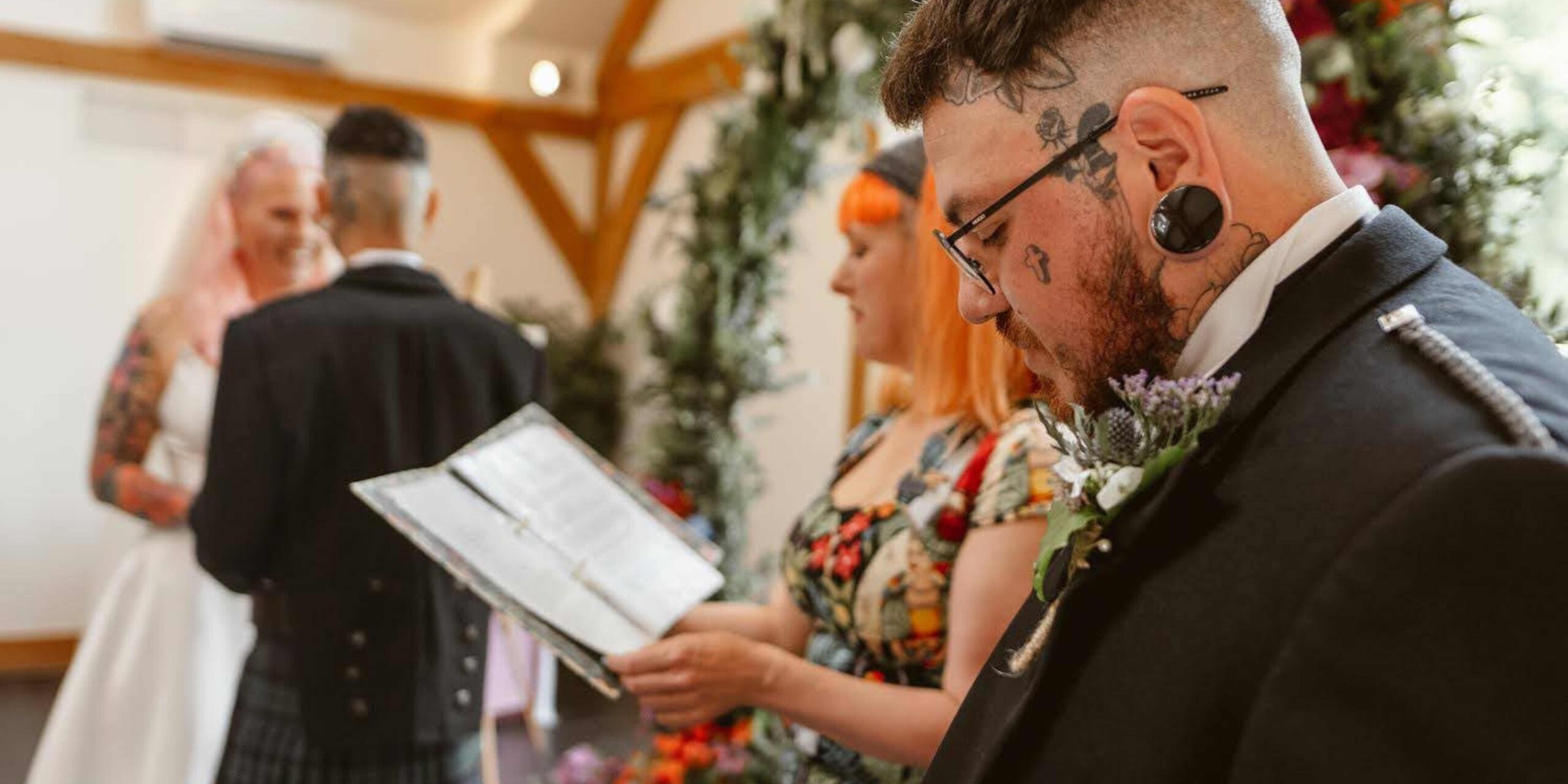 polyamorous wedding ceremonies (1) polyamorous wedding ceremonies can take many shapes and sizes. Here a couple are in the back ground and a man with tattoos and big ear rings in a suit is in the foreground