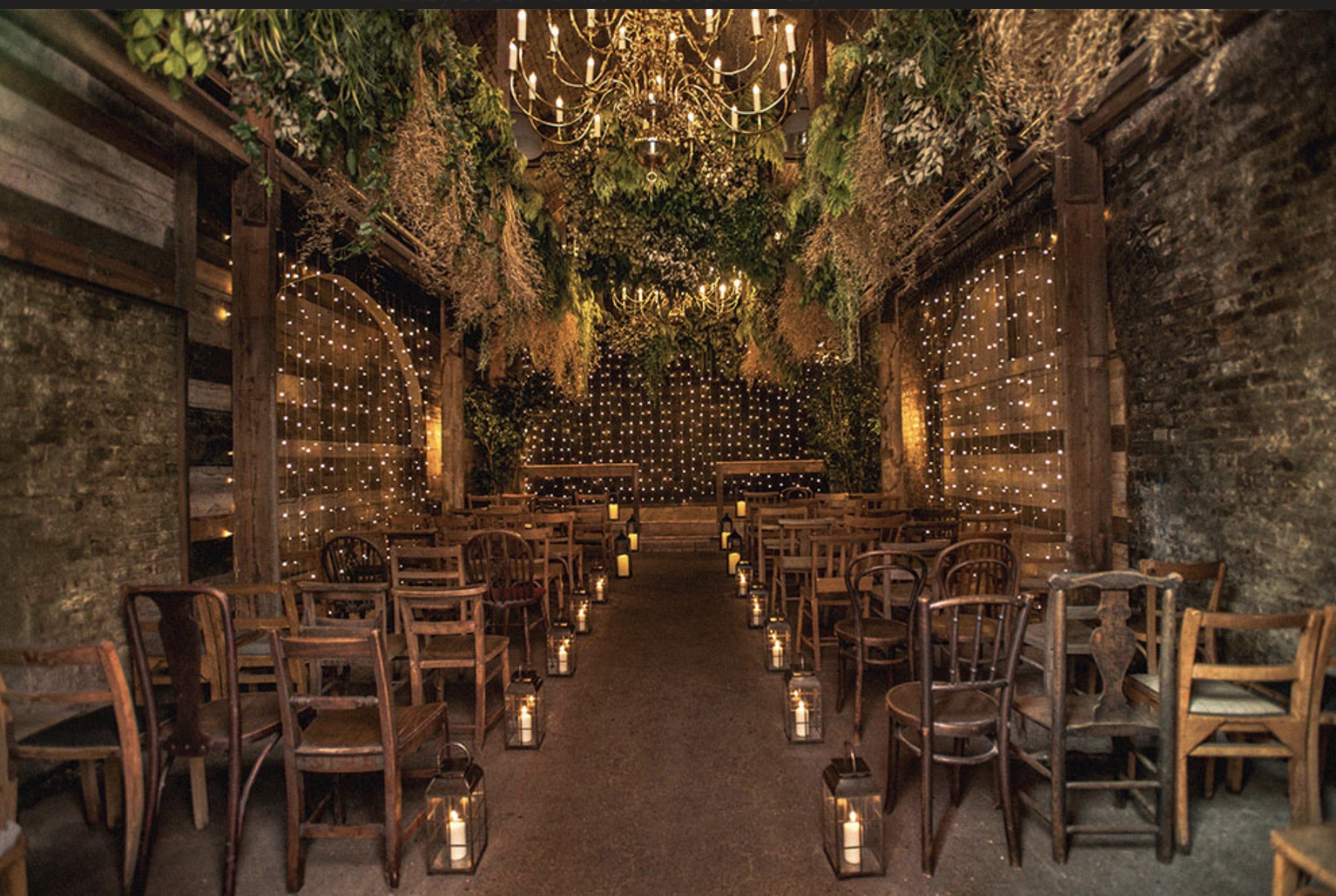 The Timber Store-unusual-london-wedding-venues Fairly lights and candles with wooden chairs and an aisle set for a wedding ceremony.