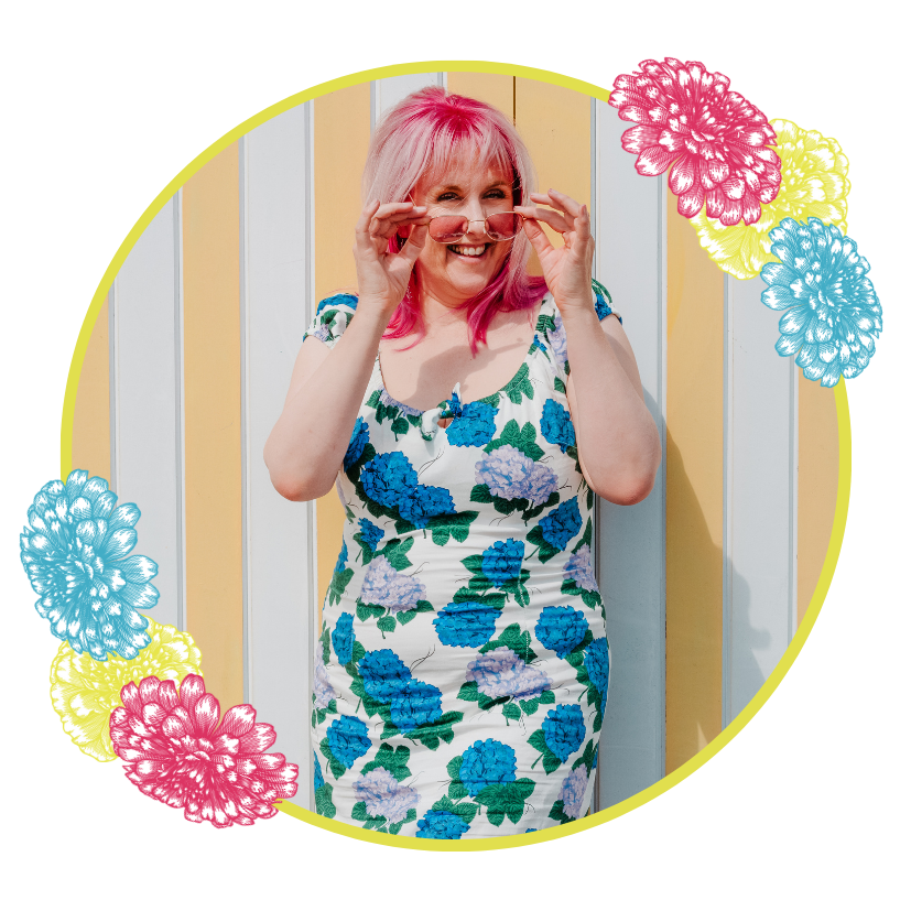 Jess-Brighton-Wedding-Celebrant Jess May Celebrant is in a forest holding a ceremony folder. She is framed by stylised flowers and is holding a flolder and smiling with love. She has pink hair.