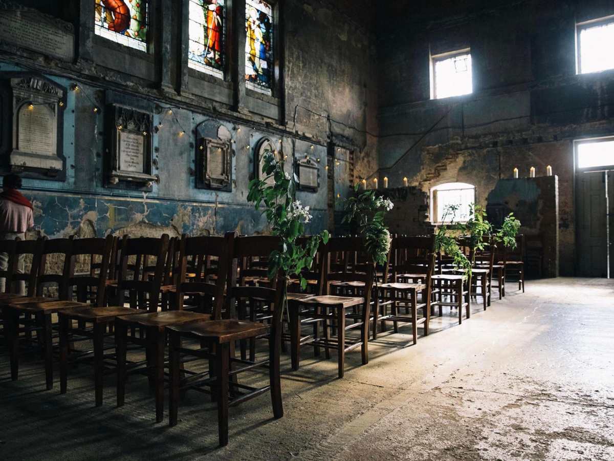 Unusual-London-wedding-venue A very ancient church in a state of ruin with chairs lined up and decorated with ivy. it is moody and characterful and has such character that you can almost smell the damp and dusty church smell. It is a formerly derelict church.