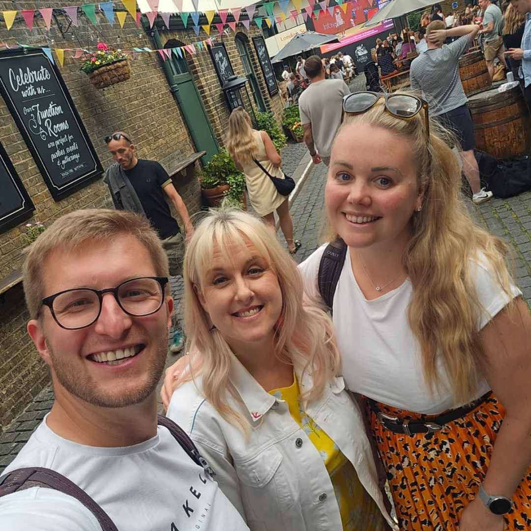 Newly Engaged couples I'm here for you! (1) Jess May between a couple taking a 'selfie'. all 3 are white, the two women have blonde hair and so does the Groom to be.